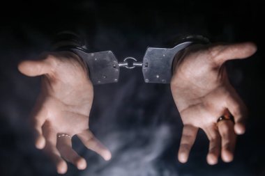 Kişinin elleri kelepçeli, etrafı karanlık ve puslu bir geçmişle çevrili, hapsedilme, mücadele ve duygusal gerilim temaları iletiliyor.