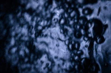 Yüzeydeki koyu renk su damlacıklarının yakın çekimi bulanık yansımaları ve karmaşık dokuları olan karamsar bir ortam sergiliyor. Artistik arka planlar için mükemmel.