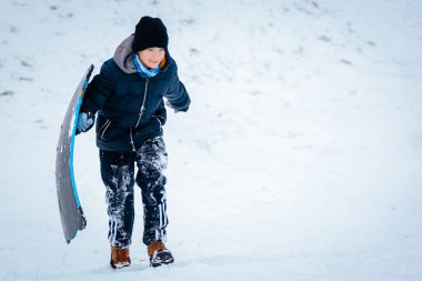 Kışın giydiği çocuk, kar ve eğlence dolu soğuk kış manzarasında kızakla, neşe ve macerayla dolu karlı bir yamaçta yükselir.