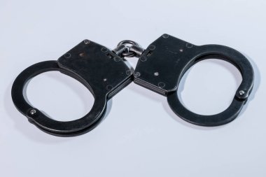 Düz bir zemine yerleştirilmiş metalik kelepçeler tasarım ve işçiliklerini vurguluyor, kolluk kuvvetleri ve güvenlik ekipmanlarını sembolize ediyor