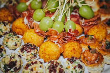 Gurme aperatifleri, peynir topları, pişirilmiş etler ve taze üzümler de dahil olmak üzere sanatsal bir şekilde sergilendi. Toplantılar ve kutlamalar için davetkar bir ortam yarattı.