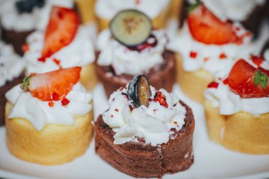 Mini desserts featuring whipped cream, strawberries, and blueberries, arranged beautifully on a platter, perfect for festive occasions and sweet indulgence