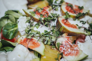 İncirli, peynirli ve mikro yeşillikli renkli salata tabakta ustalıkla hazırlanmış taze malzemeler ve sağlıklı bir yaşam tarzı seçimi.