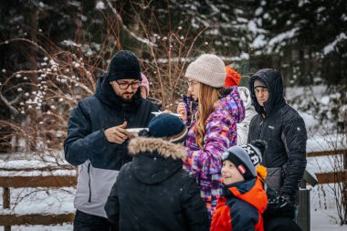 Ligatne, Letonya - 11 Ocak 2026: Çeşitli arkadaş grupları kış etkinliklerinin tadını çıkarıyor, sıcak içecekler ve kahkahaları ağaçlarla paylaşıyor