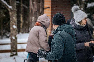 Ligatne, Letonya - 11 Ocak 2026: İnsanlar karlı bir ormanda toplandı, kalın giysiler giydiler, kış gününün ve sakin atmosferin tadını çıkardılar