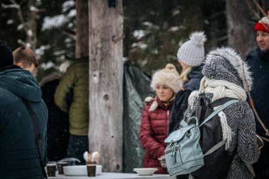 Ligatne, Letonya - 11 Ocak 2026: İnsanlar karlı ormanda toplandı, kışlık giysiler giydiler, şenlikli bir atmosferin ve fotokopi uzayıyla doğanın güzelliğinin tadını çıkardılar.