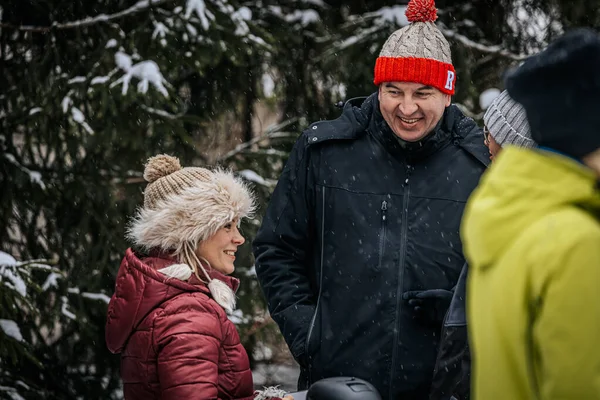 Ligatne, Letonya - 11 Ocak 2026: Çift gülümsüyor ve kışın açık havada, karla kaplı ağaçlarla çevrili, kalın ceketler ve şapkalar giyiyor.