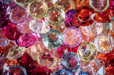 Çeşitli renk ve şekillerde çeşitli parlayan değerli taşlar ve kristaller yumuşak bir zemin üzerinde yakın bir şekilde düzenlenmiştir.