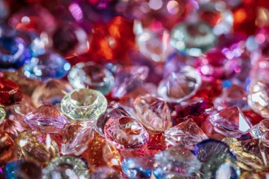 Değişik şekil ve renklerde parlak taş ve kristallerden oluşan canlı bir koleksiyon, dokulu bir yüzeye dizilmiş, parlaklıklarını ve berraklıklarını sergiliyor.