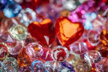 Çeşitli renk ve şekillerde çeşitli parlak taşlar ve kristaller, iki belirgin kırmızı kalp şeklinde mücevher, kopyalama alanı ile canlı bir dekoratif düzenleme oluşturur.