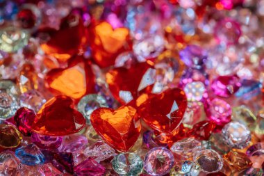 Çeşitli pırlanta taşlarda pembe, mor ve berrak renklerde çeşitli kesimli taşların arasında kırmızı kalp şeklinde kristaller bulunur ve canlı bir dekoratif düzenleme yaratır.