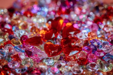 Kırmızılı, pembeli ve berrak renklere sahip çeşitli kalp ve yuvarlak şekilli pırlantalar, yaratıcı projeler için dekoratif bir gösteride bir araya getirilmiş.