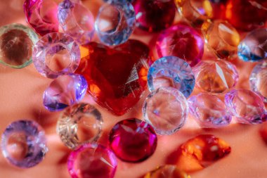 Canlı renklerde ve şekillerde çeşitli parlayan değerli taşlar ve kristaller yumuşak pembe bir arka planda sergilenmektedir, dekoratif kullanım veya sanatsal projeler için mükemmeldir.