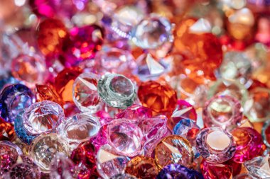 Çeşitli renklerde ve şekillerde çeşitli parlayan taşlar yansıtıcı bir yüzeye saçılmış, fotokopi alanı ile canlı ve göz alıcı bir görüntü yaratıyor.