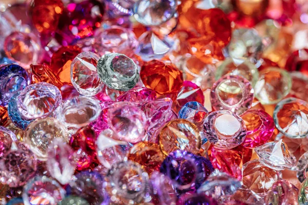 Kırmızı, pembe, mor ve berrak olmak üzere çeşitli şekil ve renklerde parlayan pırlanta taşlar, canlı bir şekilde birbirine yakın bir şekilde dizilmiş.