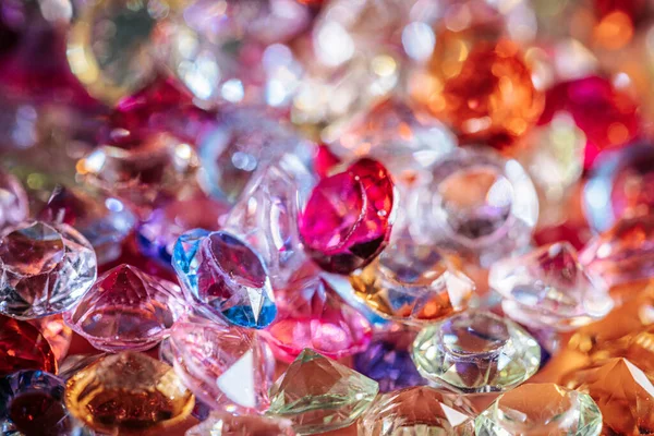 Çeşitli renk ve şekillerde parlayan değerli taşlar ve kristaller bir yüzeye dağılmış, ışığı yansıtıyor ve canlı bir görsel etki yaratıyor.