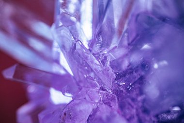 Keskin kenarları ve detaylı dokuları olan mor kristal oluşumların yakın çekimi, bulanık bir arka plan üzerine kurulmuş, mineralin benzersiz özelliklerini sergiliyor.