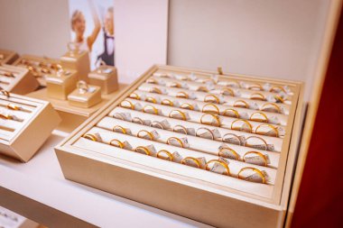 Çeşitli altın ve gümüş yüzükler, perakende sergilenen karmaşık tasarımlar ve değerli taşlar içeren bir mücevher kutusuna düzgünce yerleştirilmiştir.