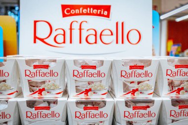 Raffaello 'nun paketlenmiş şekerlemeleri perakende alanında, arka planda marka adını ve logosunu gösteren büyük bir tabela var.
