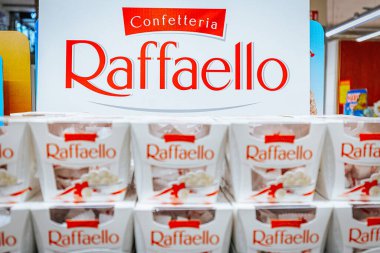 Raffaello şekerleme kutuları bir marketin rafında düzenlenmiştir, büyük bir tabela ile arka planda marka adı gösterilir