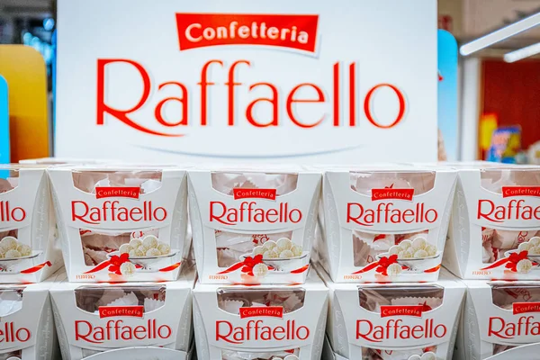 Raffaello 'nun paketlenmiş şekerlemeleri perakende alanında, arka planda marka adını ve logosunu gösteren büyük bir tabela var.