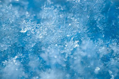 Mavi arkaplandaki kar tanelerinin detaylı görüntüleri, kış ortamına özgü şekillerini ve dokularını vurguluyor.