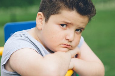Spor simülatörü üzerinde oturan üzgün şişman çocuk