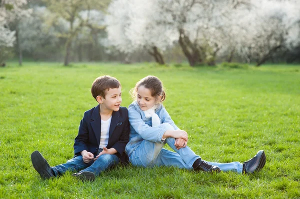 Pojke och flicka sitter på grön äng — Stockfoto