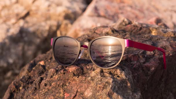 Gafas de sol que reflejan un barco que pasa sobre el fondo del atardecer — Vídeo de stock