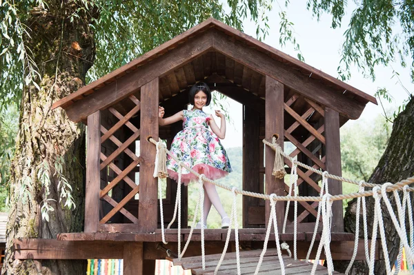 Hermosa niña en vestido de pie en la casa del árbol — Foto de Stock