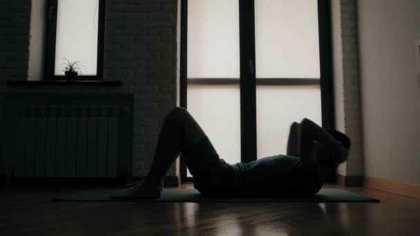 現役スポーツマンのシルエットが自立運動中に自宅に座るフィットネストレーニング — ストック動画