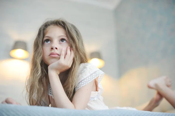 Pretty lazy idle little girl with long hair watching TV lying in bedroom — Stock Photo, Image