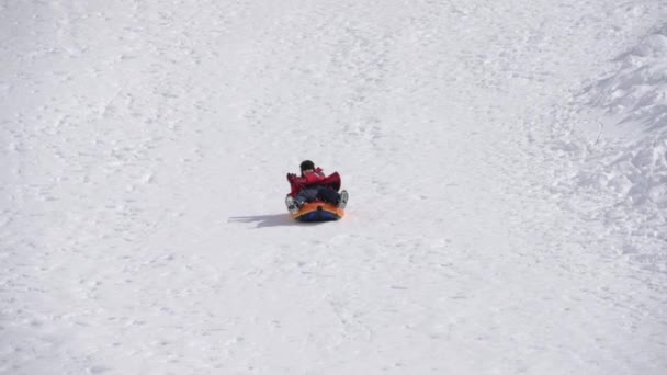 Active happy delightful kid riding sliding on rubber tube during tubing leisure fun activity — Stock Video