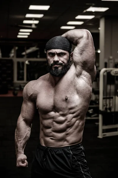 Enojado fuerte caucásico hombre en bandana mostrando abdominal y oblicuo músculo en deporte gimnasio de fitness — Foto de Stock
