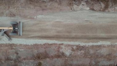 Üst manzara büyük sarı buldozer asfalt bırakmadan önce bir yolu dümdüz ediyor. Çalışan ağır inşaat makineleri yeni otoyol yapıyor.