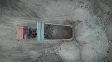 Üst manzara çöp kamyonu toprak kum inşaat alanını boşaltıyor. Büyük bir inşaat aracı taş ocağında çalışıyor. Kum boşaltıyor. Hidrolik asansörler, kamyon kaldırıyor..