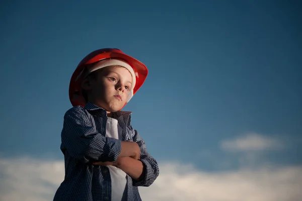 День праці в США Концепція задумливої дитини в червоному шоломі на темному нічному тлі з копіюванням простору — стокове фото