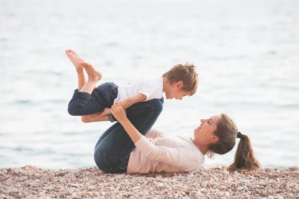 Felice deliziosa famiglia di madre adorabile giocoso e ridere bambino sulla spiaggia di mare durante le vacanze estive giochi per il tempo libero — Foto Stock