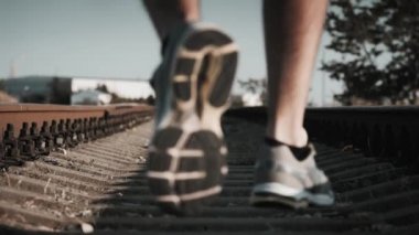 Çerçeve daha düşük açılı erkek koşucu spor ayakkabıları giyiyor demiryolu rayları üzerinden odak dışında çerçeve mesafesinde koşuyor