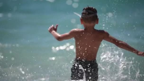 Summer leisure holiday vacation activity of little kid running in to water of blue sea with splashes in slow motion — Stock Video