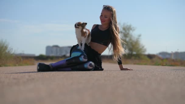 Femme heureuse tenant chihuahua chien assis sur l'asphalte ensemble — Video