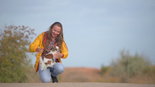 Happy young smiling caucasian woman owner meeting her small little dog with open arms leaning on knee — ストック動画