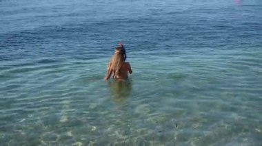 Dalış ve gözlüklü aktif bir kız yaz tatili etkinliği sırasında mavi denizin temiz sularına dalıyor.