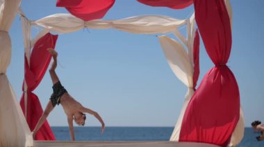 Yaz tatili aktiviteleri sırasında küçük bir çocuğun plajda takla atması yavaş çekim.