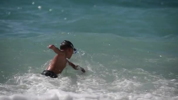 Bambino sano attivo in maschera subacquea che gioca con le onde tempestose nel mare verde blu dell'estate durante le vacanze di viaggio di svago — Video Stock