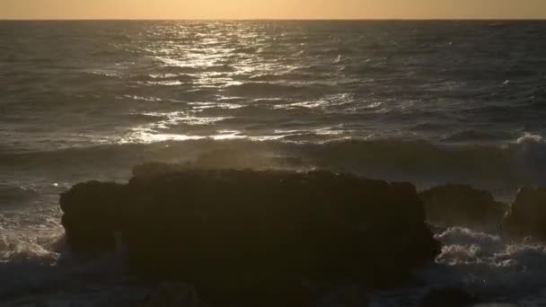 Dva lidé muž a žena plavání v bouřlivé vlny západu slunce letní moře v blízkosti skalnaté pobřeží pláže během romantické dovolené líbánky — Stock video