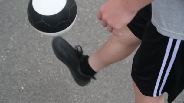 Молодой ребенок тренировки футбол с черно-белым мячом делает подсчет количество прикосновений держать держа на асфальтовом фоне — стоковое видео