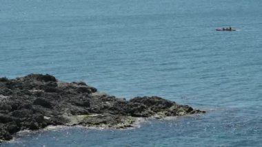 Kayalık adanın yakınlarındaki mavi denizde sportif yaşam tarzı sırasında kano sporu yapan ve dalış yapan aktif insanlar yaz tatili aktiviteleri sırasında aktifler.