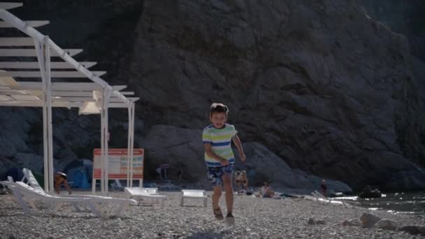Little happy healthy small kid in jersey and shorts running on summer beach during holiday leisure vacation recreation — Stock Video