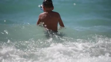 Dalış maskeli çocuk yaz tatili etkinliği sırasında fırtınalı dalgalı denizde dalıyor.